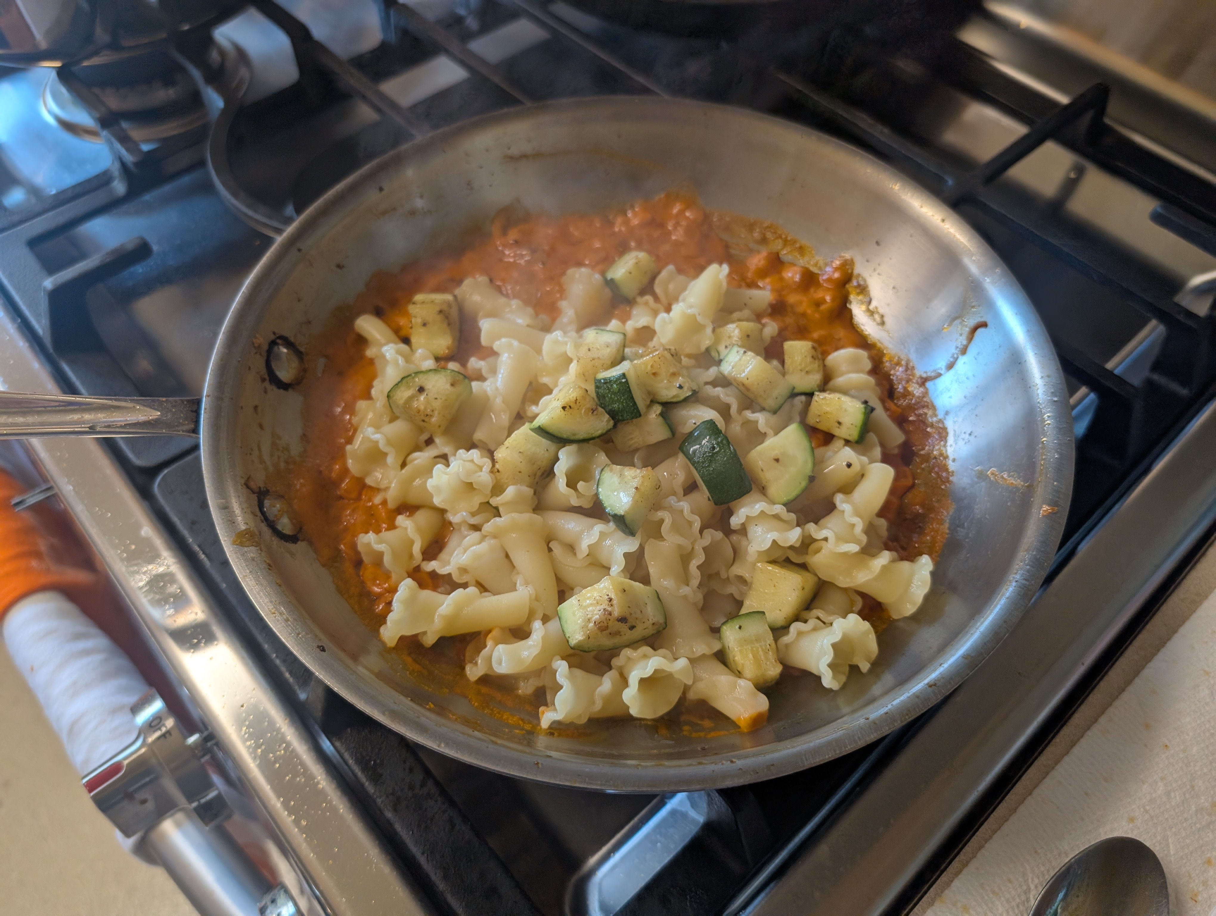 Adding pasta and zucchini into the sauce